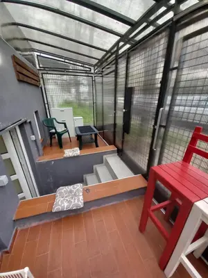 a screened in porch with a red table and chairs at Under the Tree in Novi Beograd