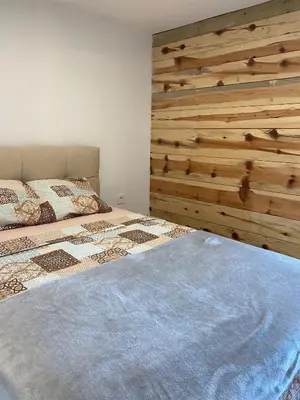 a bedroom with a bed and a wooden wall at Tiny house Neny Fruška gora in Velika Remeta