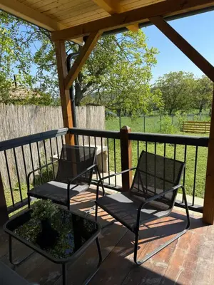 two chairs on a porch with a view of a field at Tiny house Neny Fruška gora in Velika Remeta