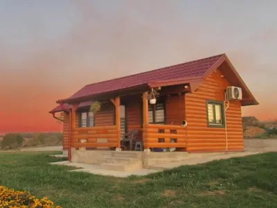 a cabin in a field with a sunset in the background at Brvnara Staničić in Arandjelovac