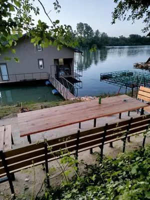 a house on a dock on a lake with a bench at Splav na dan AXA in Barič