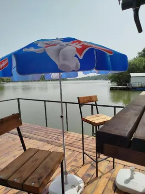an umbrella on a deck with a table and chairs at Splav na dan AXA in Barič