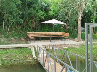 a picnic table with an umbrella next to a pond at Splav na dan AXA in Barič