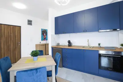a kitchen with blue cabinets and a wooden table at Airport Belgrade Apartments in Surčin