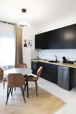 a kitchen with black cabinets and a table and chairs at Airport Belgrade Apartments in Surčin