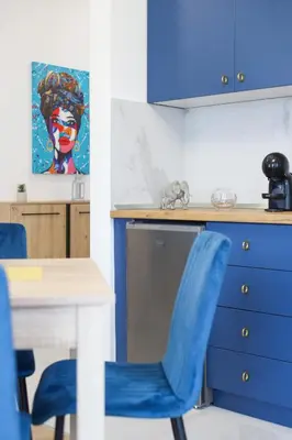a kitchen with a table and blue chairs at Airport Belgrade Apartments in Surčin