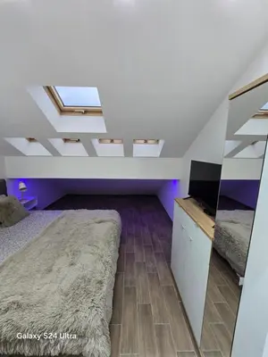 a attic bedroom with a bed and a television at IDILA SPA New Belgrade in Novi Beograd