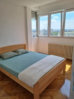 a large bed in a room with two windows at Jela in Belgrade