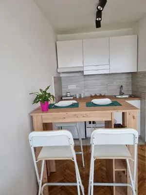 a kitchen with a wooden table and two white stools at Jela in Belgrade