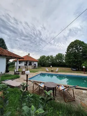 a swimming pool with a table and chairs next to a house at Kosmajski Beg: Vaša privatna vikendica sa bazenom in Nemenikuće