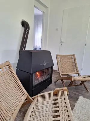 a living room with a fireplace and two chairs at Šumska Kosmaj in Nemenikuće
