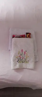 a white towel with a vase of flowers on a bed at Lenny's Apartment in Čukarica
