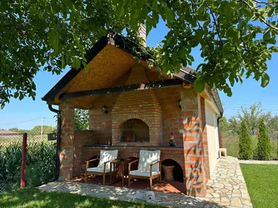a brick fireplace with a table and chairs in a yard at Apartman Aerodrom in Surčin