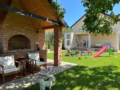 a backyard with a brick fireplace and a playground with toys at Apartman Aerodrom in Surčin
