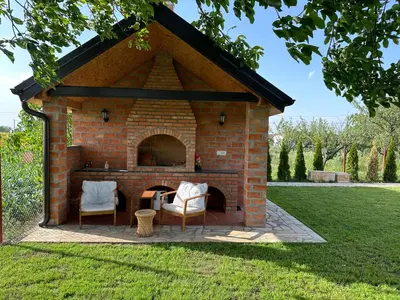 a brick fireplace with two chairs in a yard at Apartman Aerodrom in Surčin