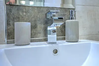 a bathroom sink with a faucet and two candles on it at Vračar Central Apartment in Belgrade