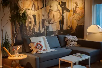 a blue couch in a living room with a painting at URBAN GREEN Corner with a Story in Belgrade