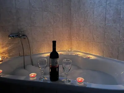 a bottle of wine and two wine glasses in a bath tub at GOLD Apartman in Mirijevo