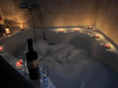a bath tub covered in snow with wine glasses and lights at GOLD Apartman in Mirijevo
