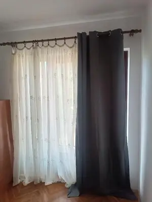 a window with white curtains in a room at GOLD Apartman in Mirijevo