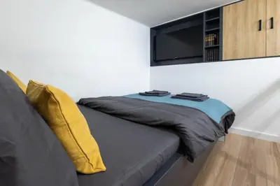 a bedroom with a couch with a tv on the wall at Sunflower Apartment in Belgrade