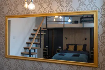 a mirror reflecting a bedroom with a bed and a staircase at Sunflower Apartment in Belgrade