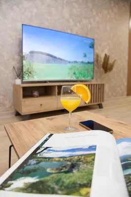 a glass of orange juice and a book on a table at Golden hill Vinča in Vinča