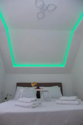 a white bed with a green light on the ceiling at Golden hill Vinča in Vinča
