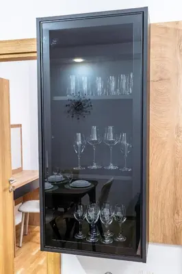 a glass display case with wine glasses on a table at Apartman Kolarević in Arandjelovac