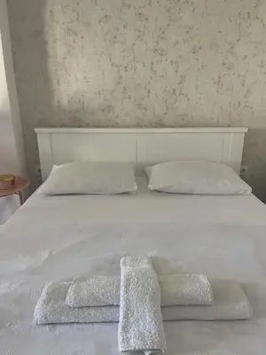 a white bed with two towels on top of it at BeoAir apartments in Surčin