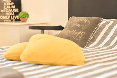 a bed with yellow pillows and a pillow that reads happy new year at Hedonist Spa-ABlok 1 in Belgrade