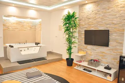 a bathroom with a tub and a tv on a brick wall at Hedonist Spa-ABlok 1 in Belgrade