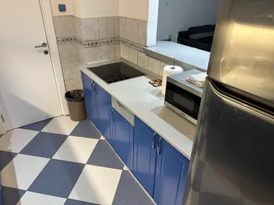 a kitchen with blue cabinets and a checkered floor at Apartman BK LUX in Belgrade