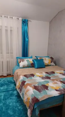 a bedroom with a bed with a colorful comforter and pillows at Plavi Tirkiz in Pančevo
