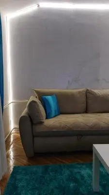 a couch with a blue pillow in a living room at Plavi Tirkiz in Pančevo