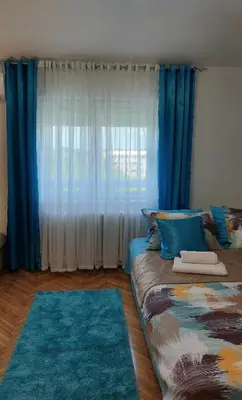 a room with a couch with blue curtains and blue rugs at Plavi Tirkiz in Pančevo