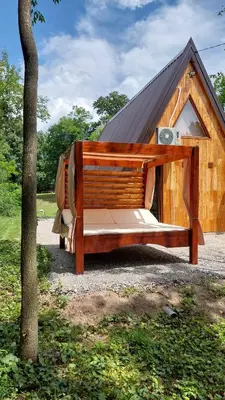 a large wooden bed in front of a house at Luna kuća- Devojački bunar in Novi Vladimirovac