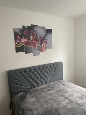 a bedroom with a bed with four pictures on the wall at Apartman Fame near Airport in Surčin