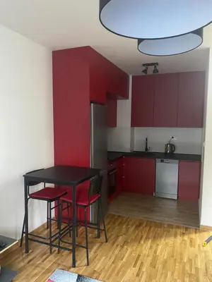 a kitchen with red cabinets and a black table and chairs at Apartman Fame near Airport in Surčin