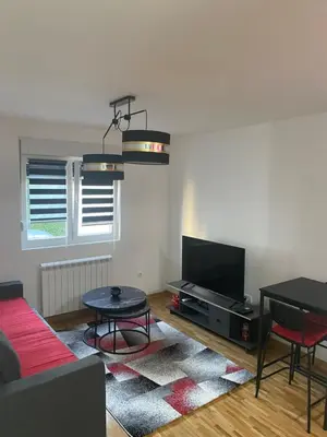 a living room with a couch and a tv and a table at Apartman Fame near Airport in Surčin