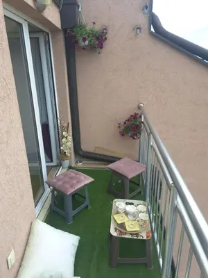 a balcony with two stools and a table with food at Lux Apartman 7 in Voždovac