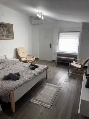 a bedroom with a bed and a chair and a window at MELIORA Apartment in Belgrade