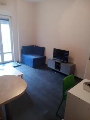 a living room with a blue couch and a tv at Flower Square Studio in Belgrade