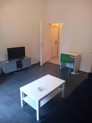 a living room with a white table and a green chair at Flower Square Studio in Belgrade