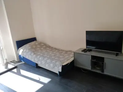 a bedroom with a bed and a flat screen tv at Flower Square Studio in Belgrade