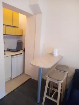 a small kitchen with a table and two stools at Flower Square Studio in Belgrade