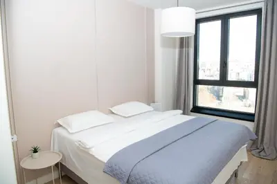 a white bedroom with a large bed and a window at Belgrade Waterfront Promenade in Belgrade