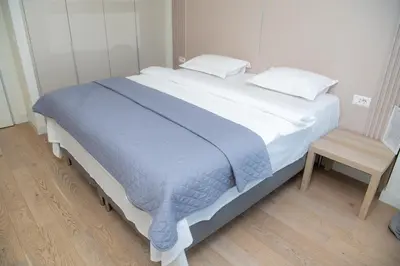 a large white bed with a blue blanket on it at Belgrade Waterfront Promenade in Belgrade