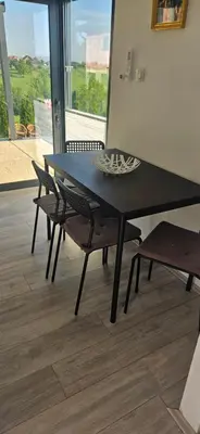 a black dining room table and chairs with a window at Vila Duplex in Lipovica