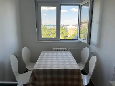 a dining room with a table and two windows at Comfort & Style Panoramic Urban Retreat in Novi Beograd